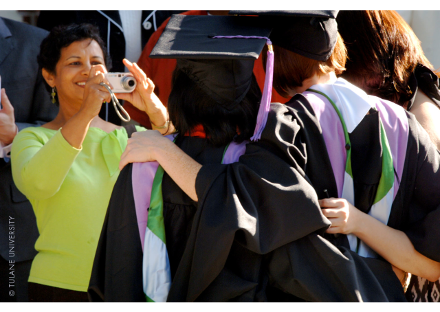 Image of a proud relative photographing a group of graduates