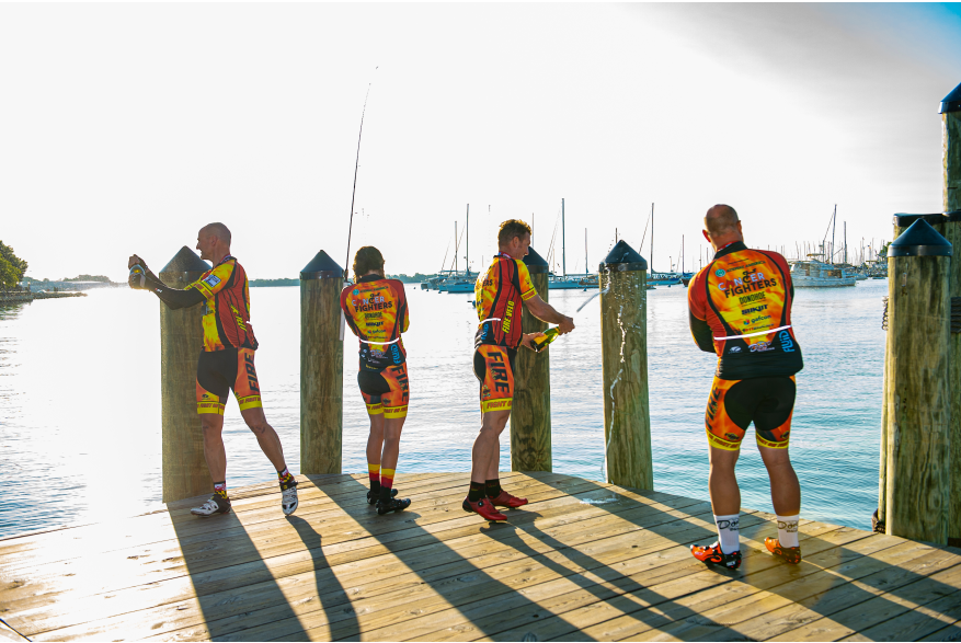 4 male bikers celebrate their finish of the Race Across America at Annapolis City Dock