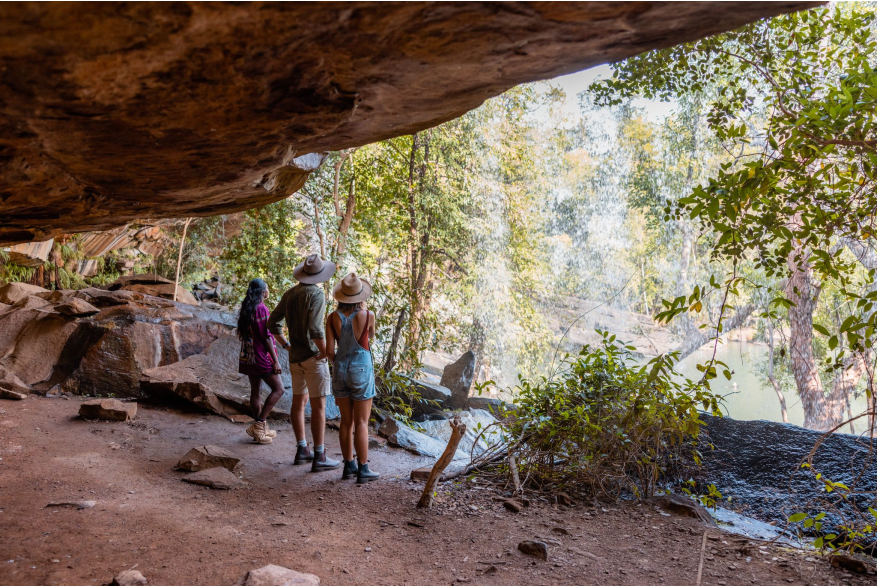 A tour guide stands with two tour guests looking out at a waterfall