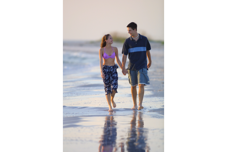 Young couple walking on the beach holding hands
