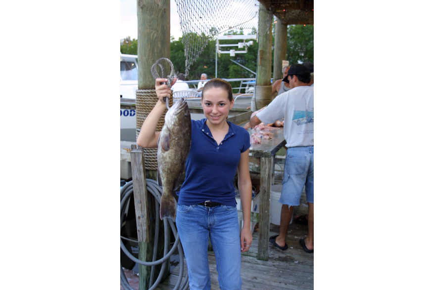 Young woman holding up a large mangrove grouper