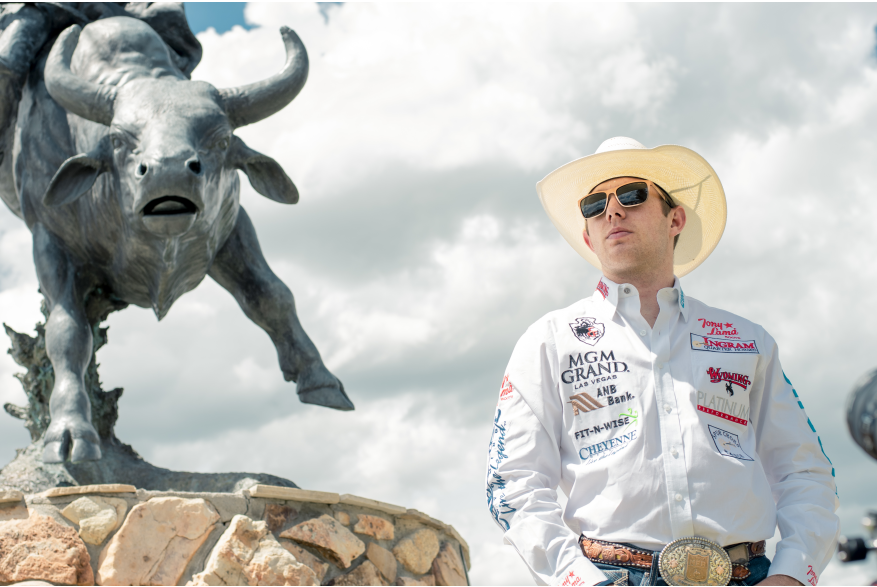 a rodeo cowboy stands next to a sculpture of a bull