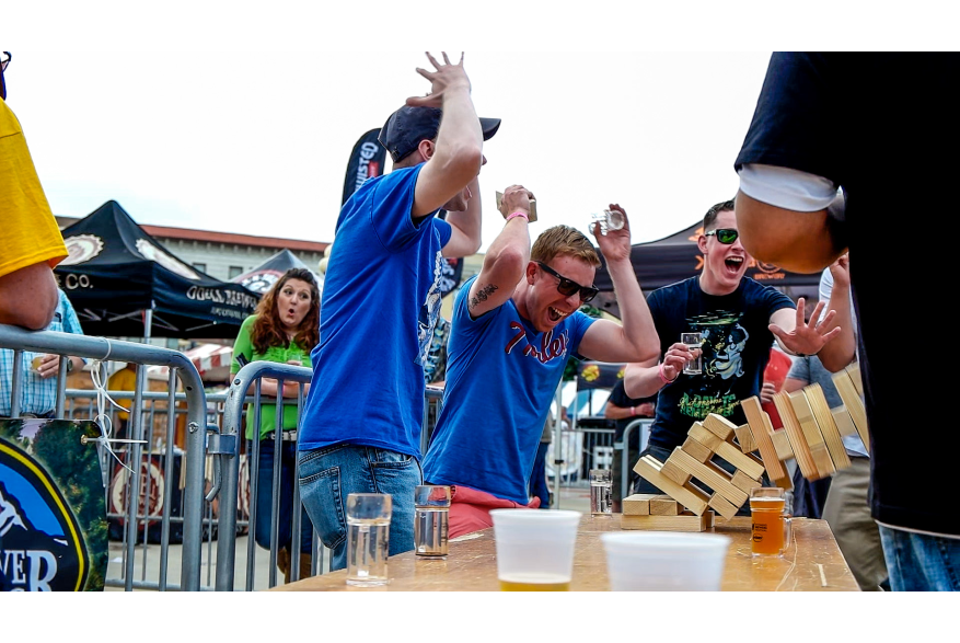 Men react as their jenga tower falls at the Wyoming Brewers Festival