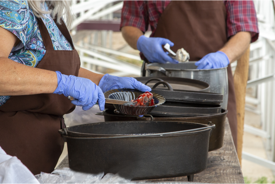 woman dishing up cobbler from a cast iron dutch oven