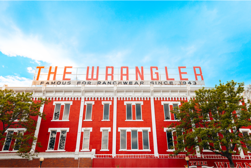 A photo of the red and white brick building with the famous "The Wrangler: Famous for Ranchwear Since 1934".