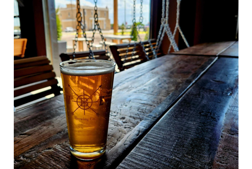 A glass of craft beer sitting on a rustic wooden table at Westby Edge Brewing, one of the best spots for craft drinks and local vibes, and a must-visit hidden gem and great for something to do in Cheyenne.