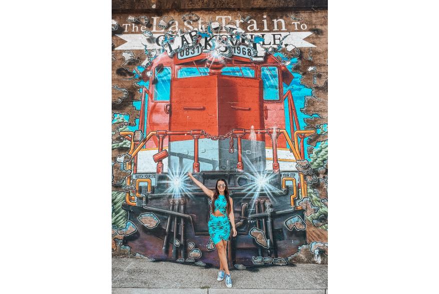 lady in front of a large train mural