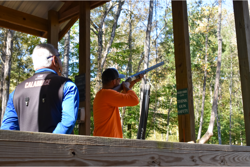 two men at a target clay shooting station in the woods