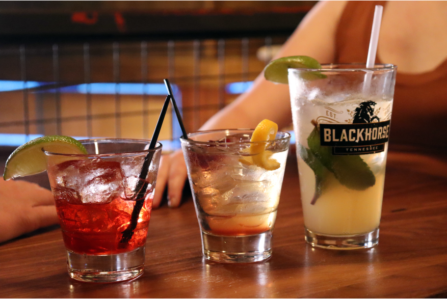 a couple at a bar table with three drinks