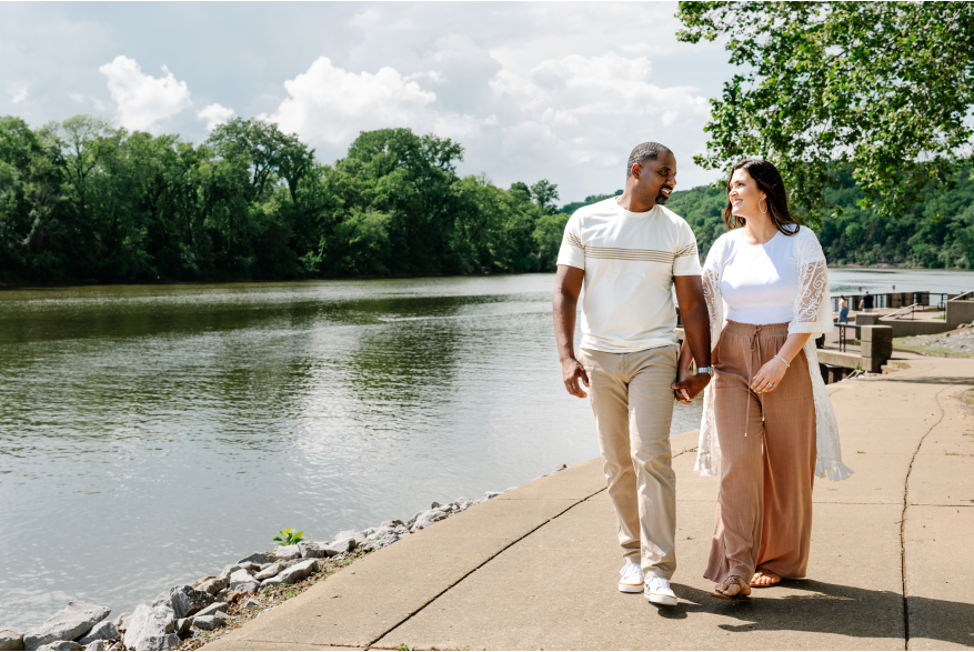 a man and woman walk along a riverside path