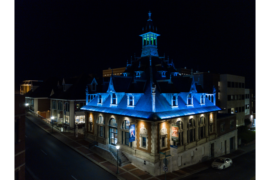 a historic, spired building with a blue under-lit rooftop
