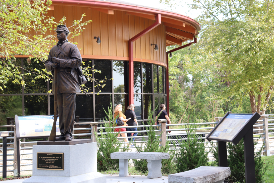statue of an African American soldier beside a visitor center