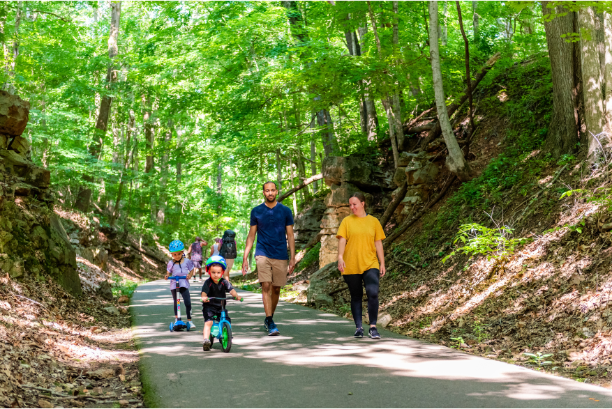 family with children on bikes walk the Clarksville Greenway