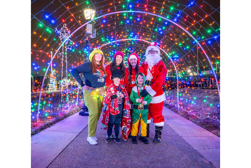 festive group of people with Santa under a light tunnel