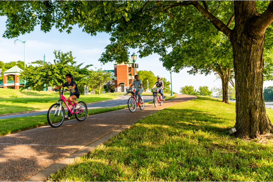 family riding bikes on a riverwalk