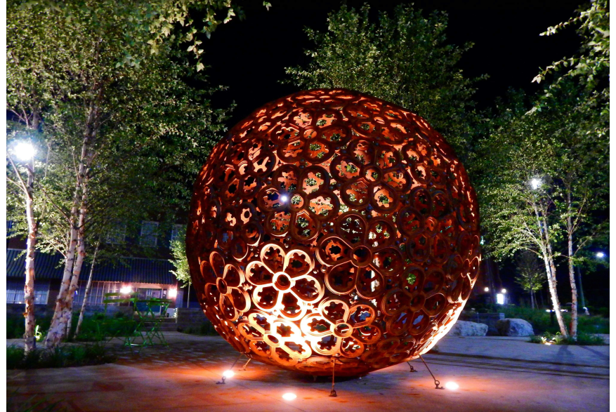 large rosette-patterned sphere in a park at night