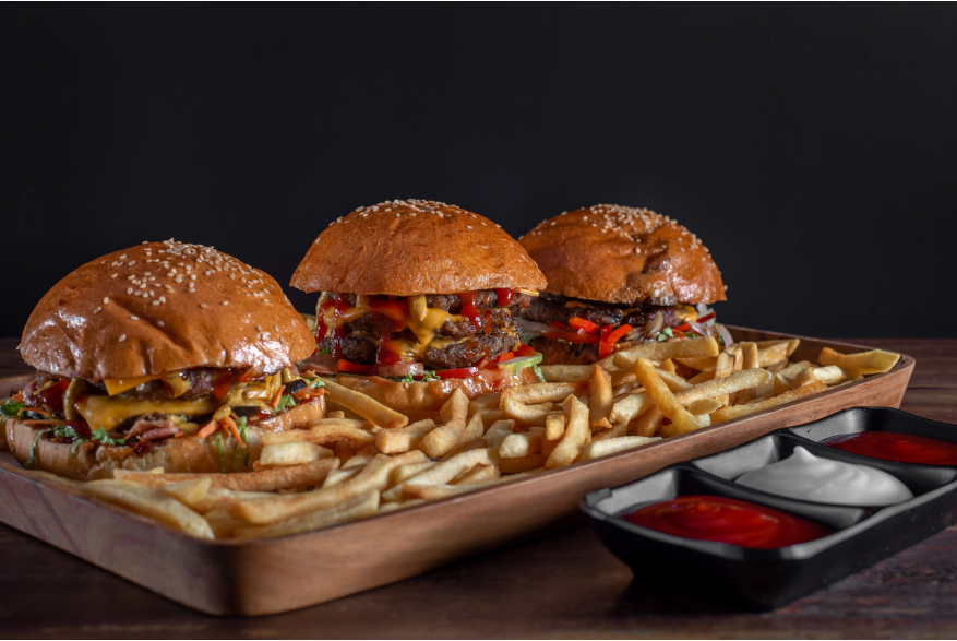 three burgers on a plate with fries and sauces
