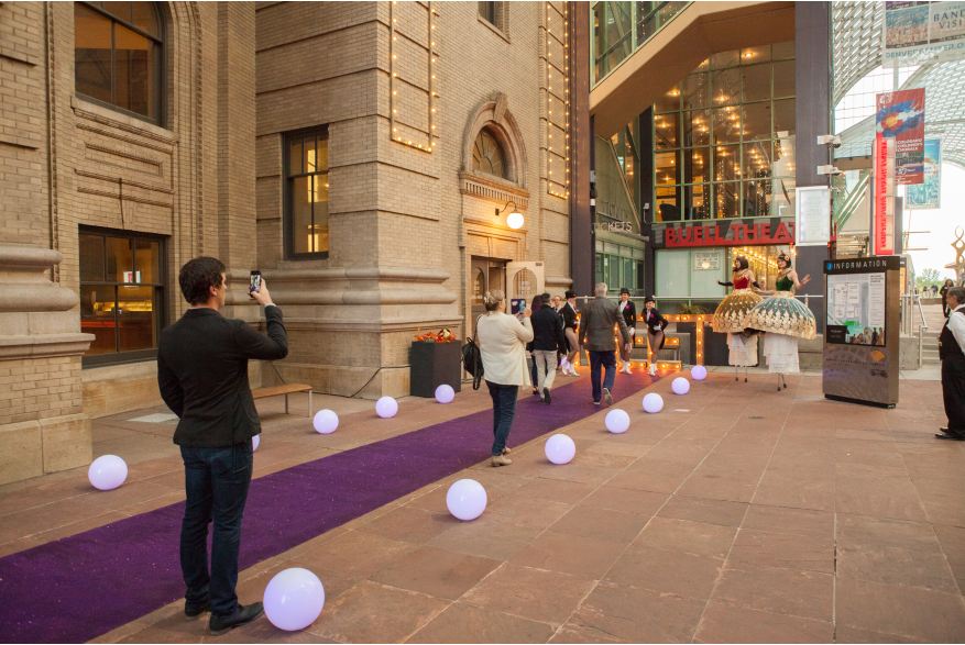 people walking down purple carpet strip in performing arts complex