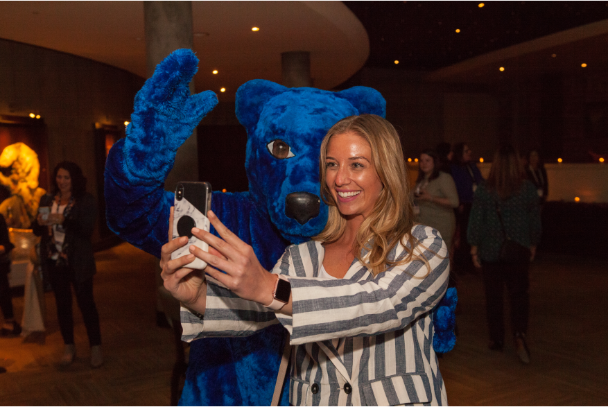 Attendee taking photo with a Blue Bear mascot