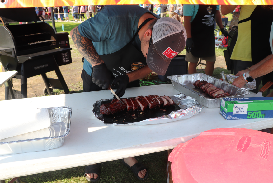 A man cutting a smoked rack of ribs into individual ribs.