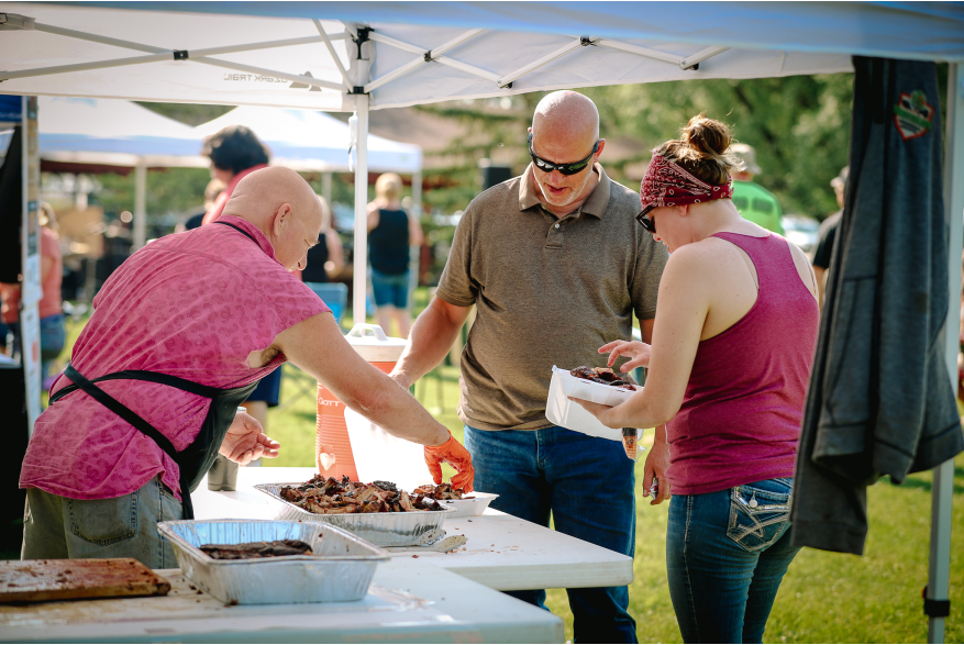 A man serving ribs to a man and a woman.