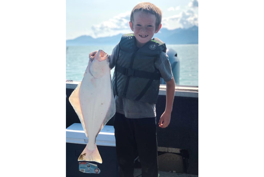 young boy holding halibut catch