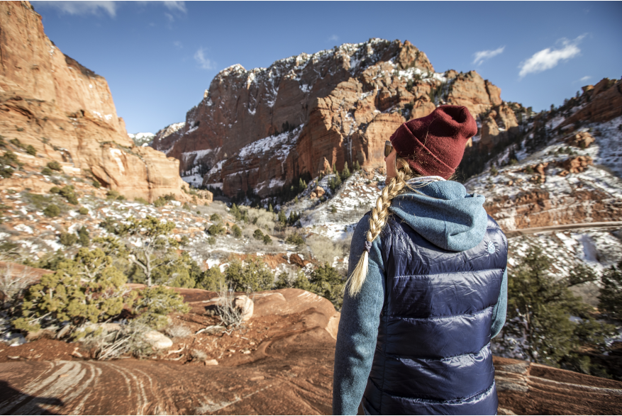 Woman dressed for colder weather hiking into red rock formations in Kolob Canyons, the North Side of Zion National Park.