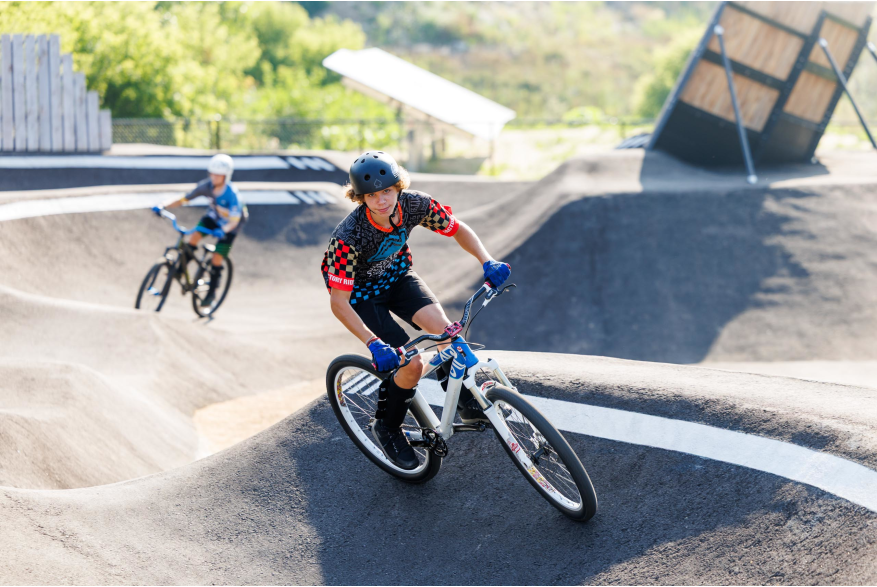 2 kids riding in a pump track