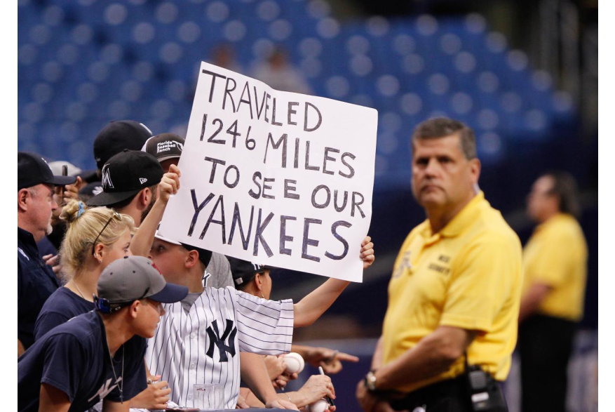 New York Yankees fan holding a sign reading "TRAVELED 1246 MILES TO SEE OUR YANKEES"