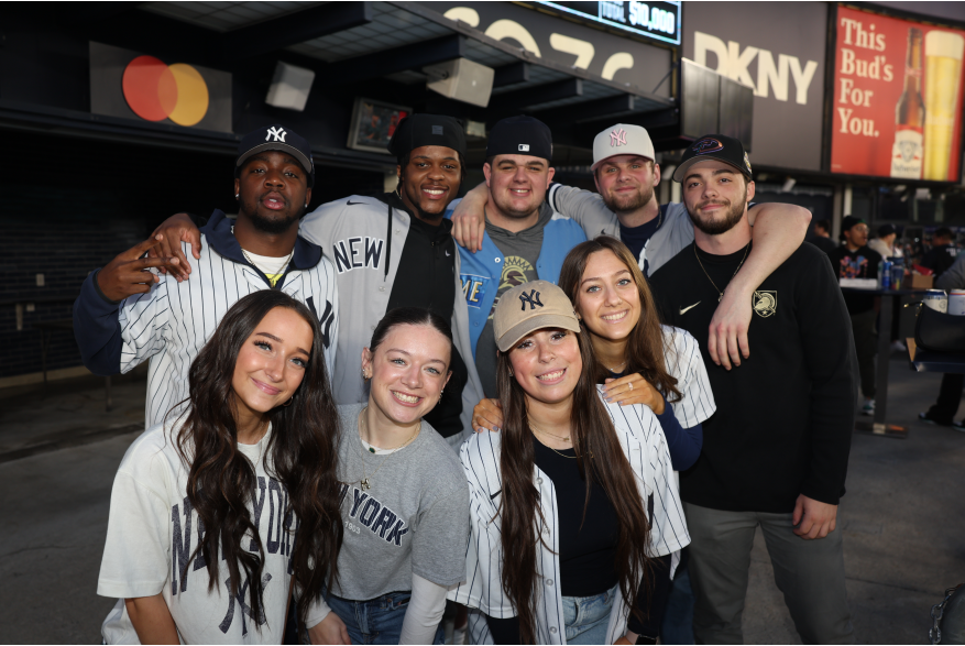 Group of Yankees fans gathered at Yankees stadium posing for a picture