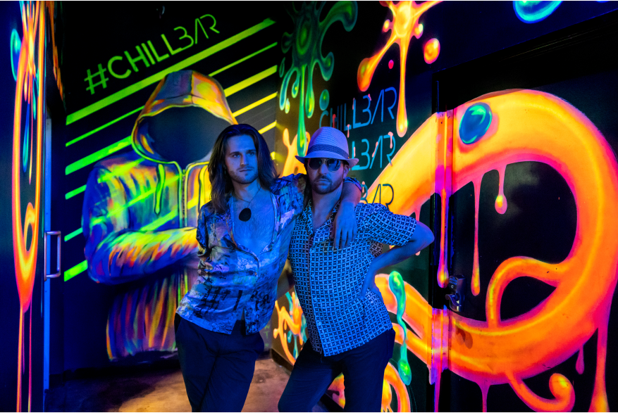 Two guays hanging out at a gay bar.