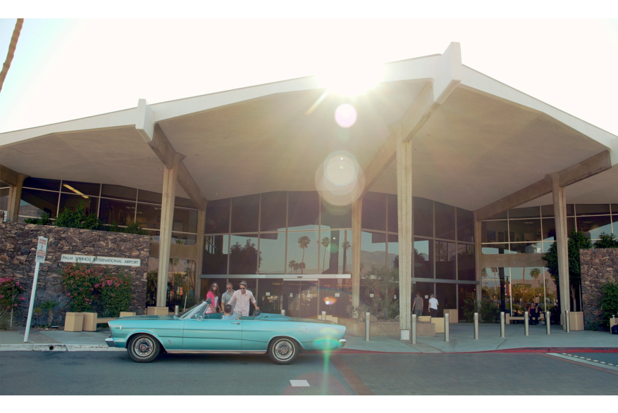 Three people in vintage car in front of PSP.