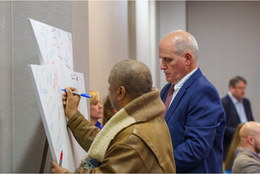 Women and man sign the keystone in support of Monroe County's America250PA initiative