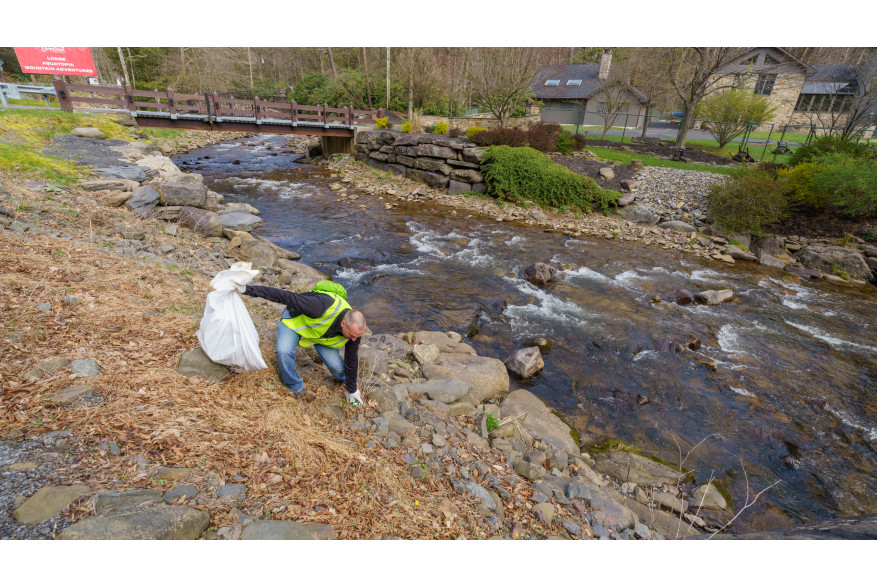 Trash being picked up along a creek