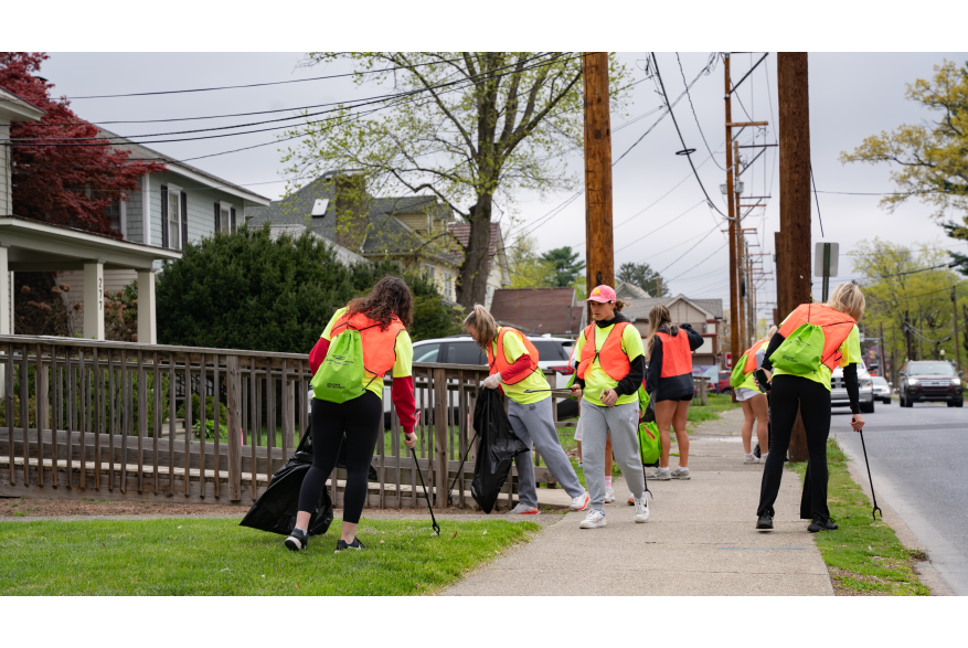Group of students picking up trash along the sidewalk
