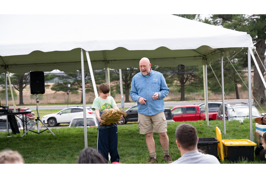 Boy holding a giant tortoise at an Earth Day Festival