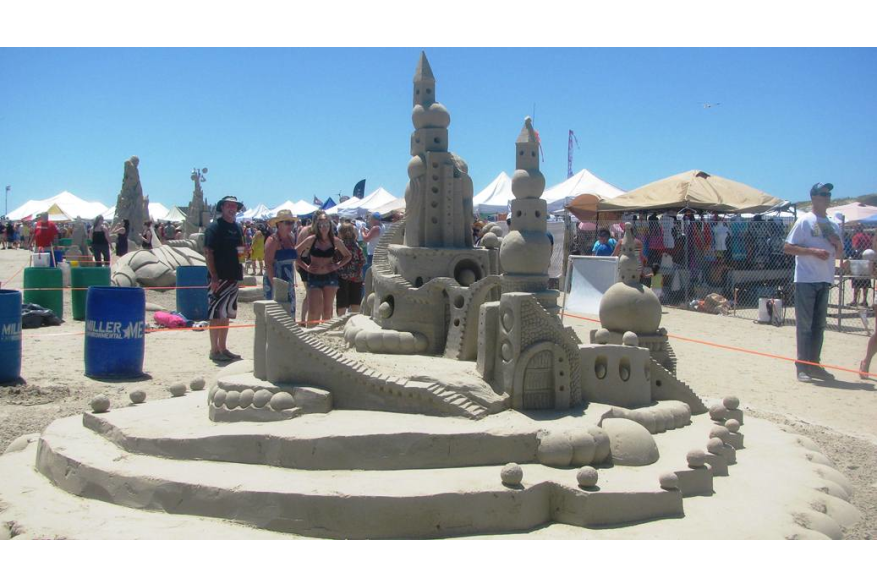 People standing around a sandcastle at Texas SandFest, showcasing impressive sand art and sculptures
