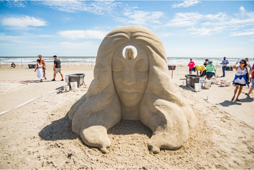 Sand sculpture of a women wiht a hole in the middle of ther head showing a smaller version of her.