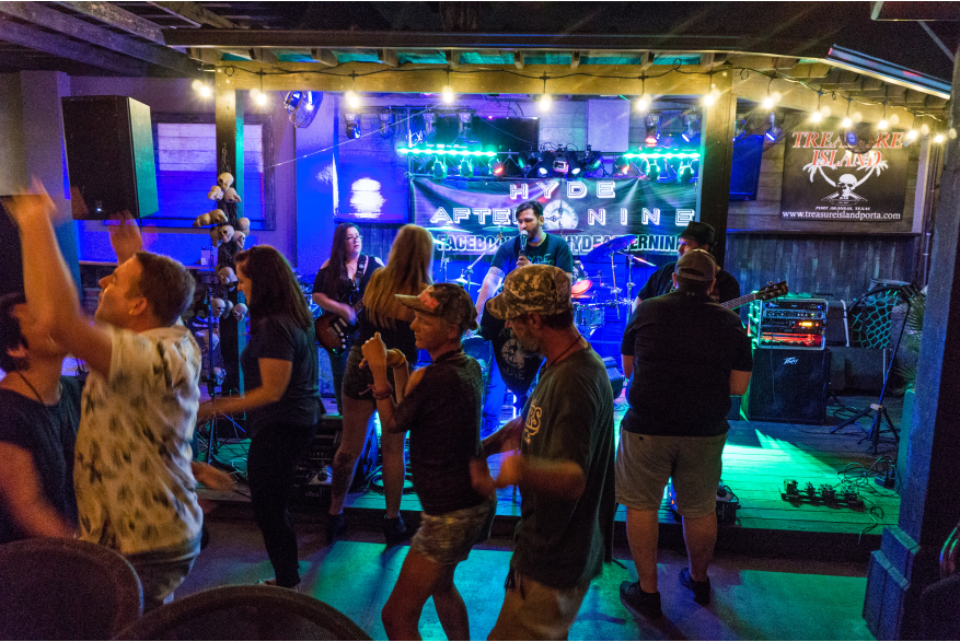 A group dances in front of a band playing on a small stage.