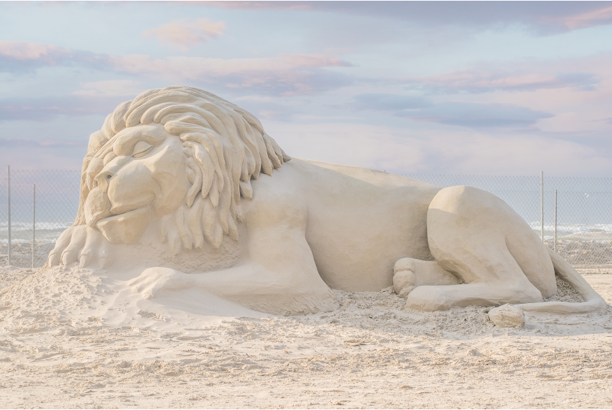 Large sleeping lion sculpture made of sand.
