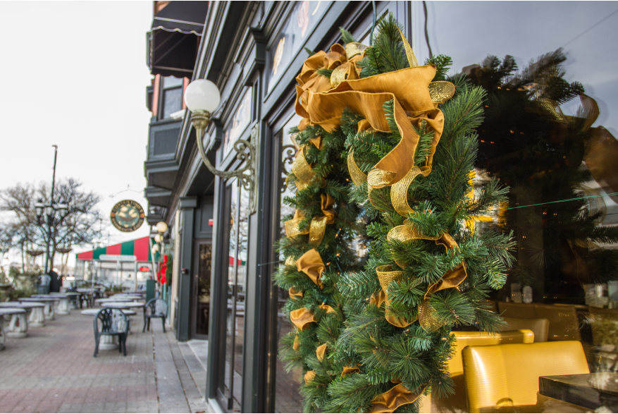 Holiday wreath with gold ribbons hanging on a reflective window