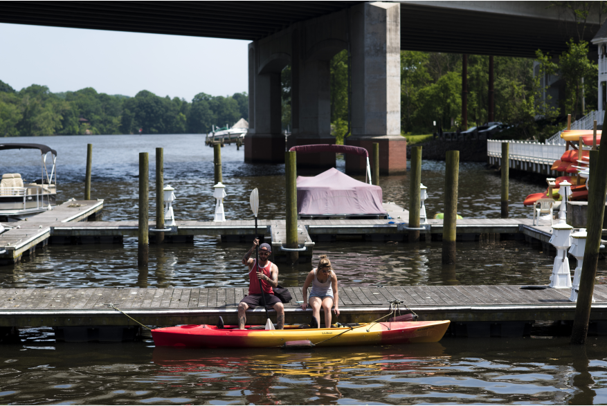 Two people on a boardwalk getting ready to get into a kayak