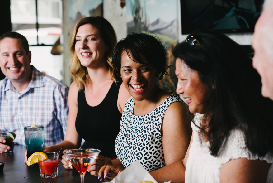 A group of people sitting at a bar smiling