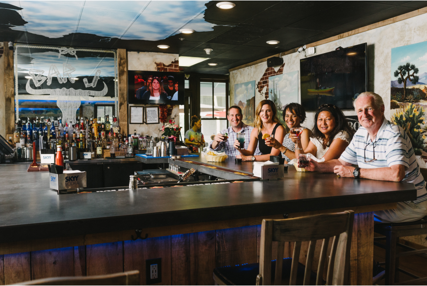 A group of people sitting at a bar smiling