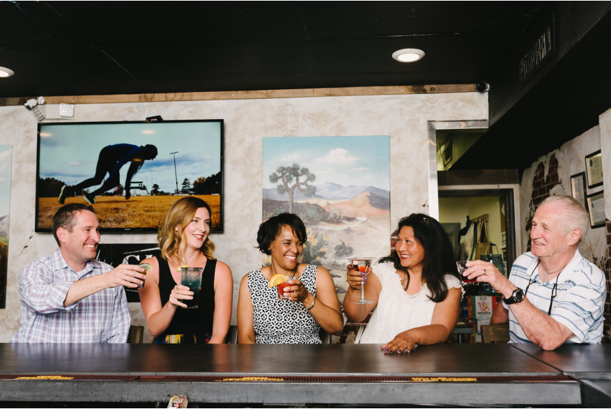 A group of people sitting at a bar smiling