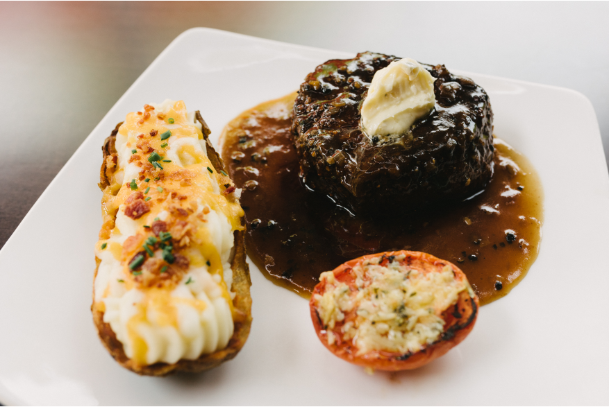 A plate of steak with a potato