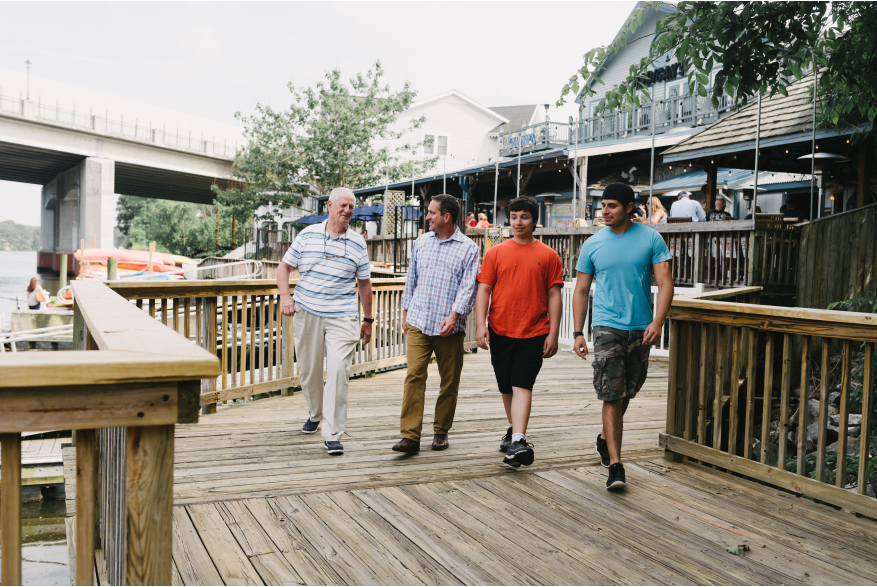 Four men walking along a boardwalk