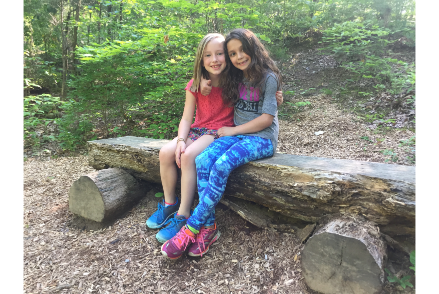 Two girls sitting together on a log