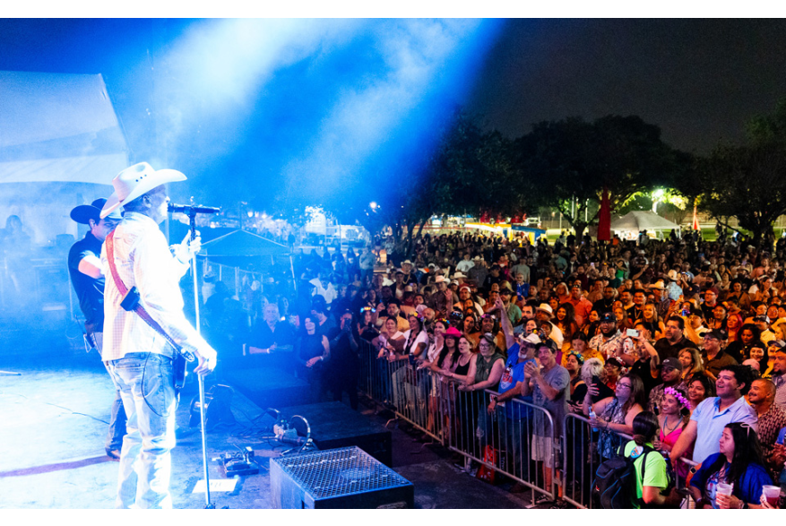 Man playing guitar and singing to crowd at Fiesta San Antonio.