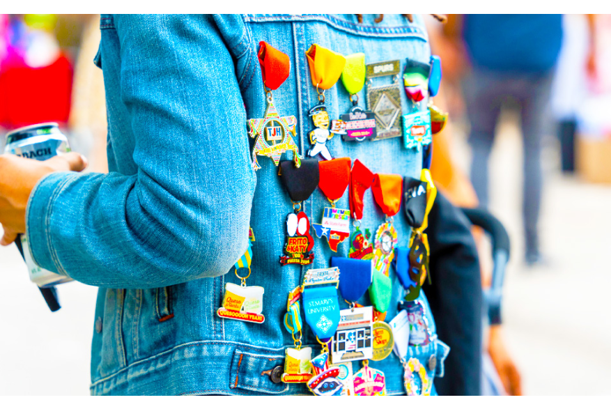 Back of person wearing jean jacket filled with Fiesta medals.